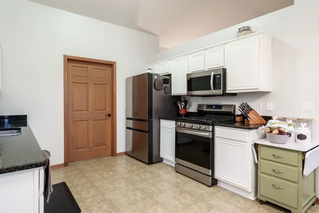 a kitchen with stainless steel appliances granite countertop a stove top oven a sink dishwasher a dining table and chairs with wooden floor