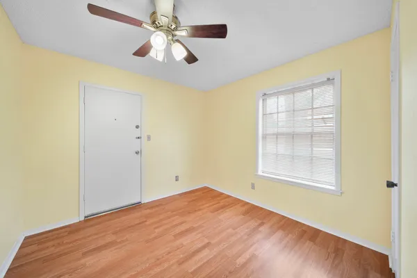 an empty room with windows and fan