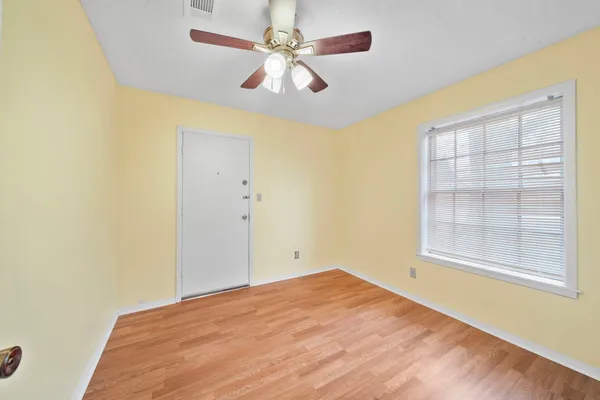 an empty room with windows and fan