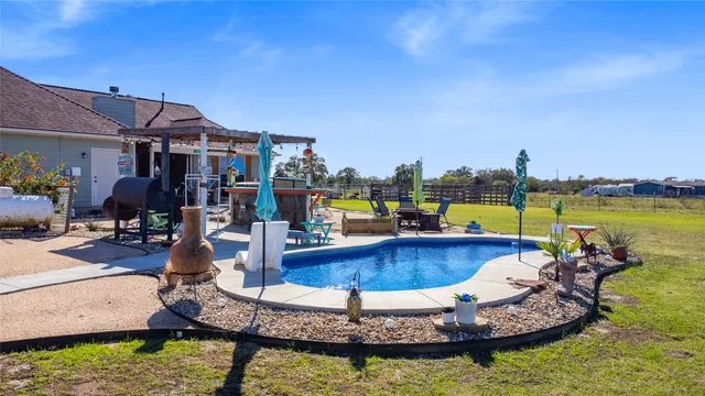 a swimming pool with outdoor seating and yard in back