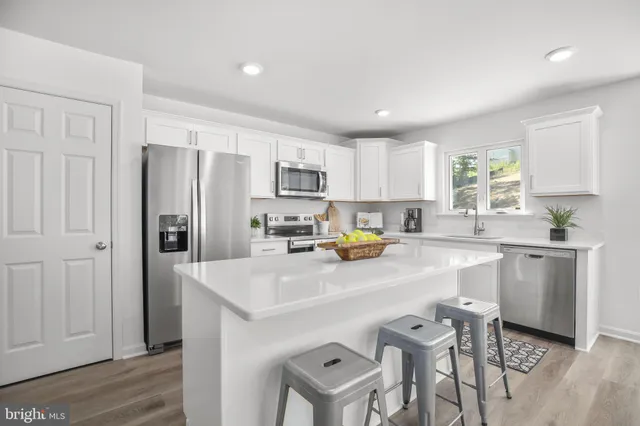 a kitchen with a sink a refrigerator and white cabinets
