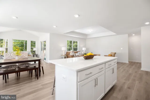 a kitchen with white cabinets appliances and dining table