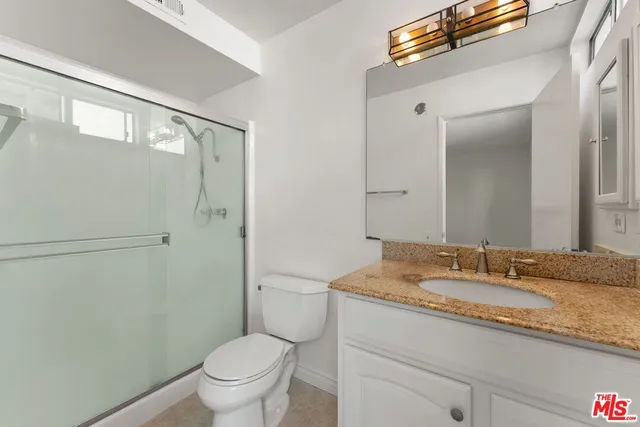 a bathroom with a granite countertop sink toilet and shower