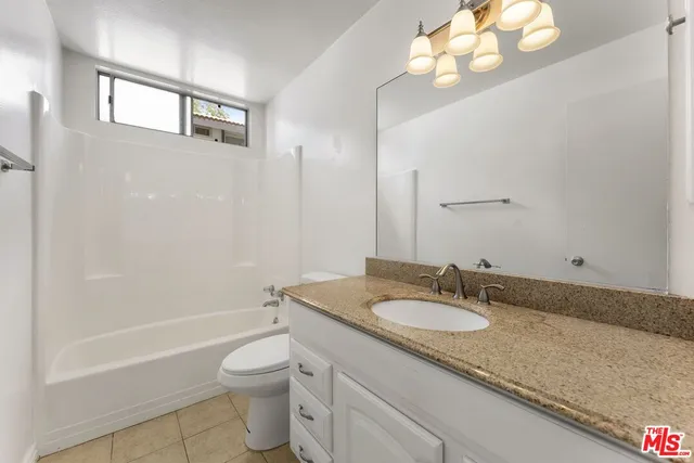 a bathroom with a granite countertop sink a toilet and shower