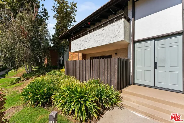 a backyard of a house with plants and trees with wooden fence