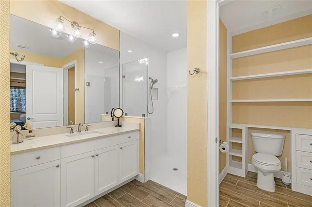 a bathroom with a double vanity sink a toilet and a shower