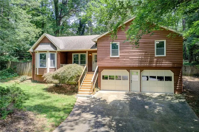 a view of a house with a yard and large tree