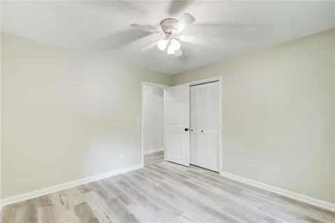 an empty room with wooden floor and ceiling fan
