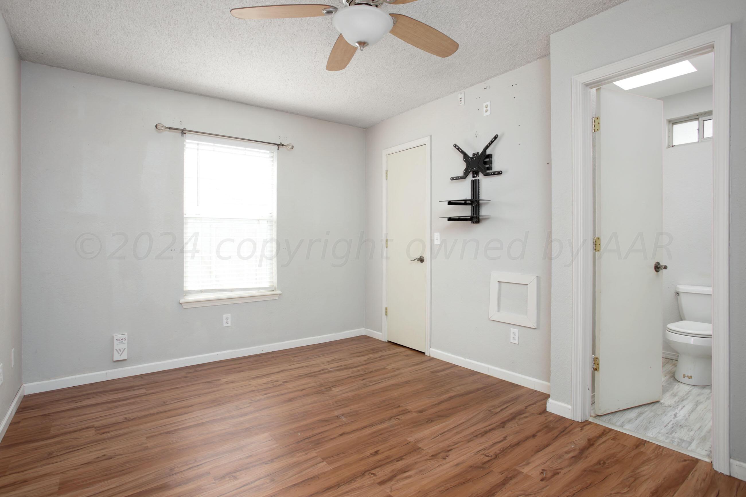 4625 South Travis Street Amarillo, TX 79110 - Photo 12 of 24 wooden floor in an empty room with a window