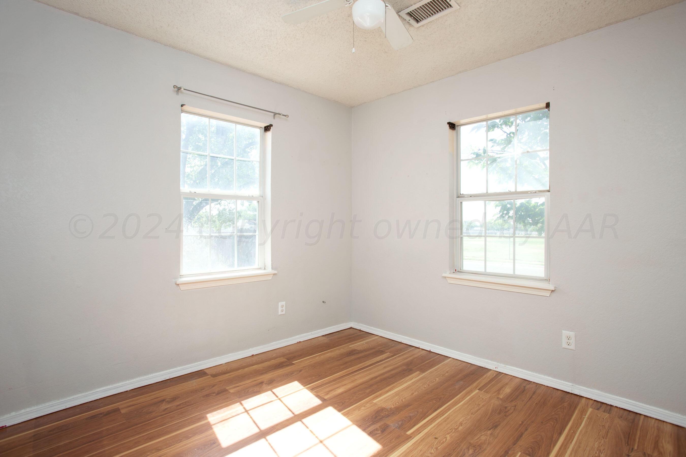 4625 South Travis Street Amarillo, TX 79110 - Photo 17 of 24 an empty room with wooden floor and windows