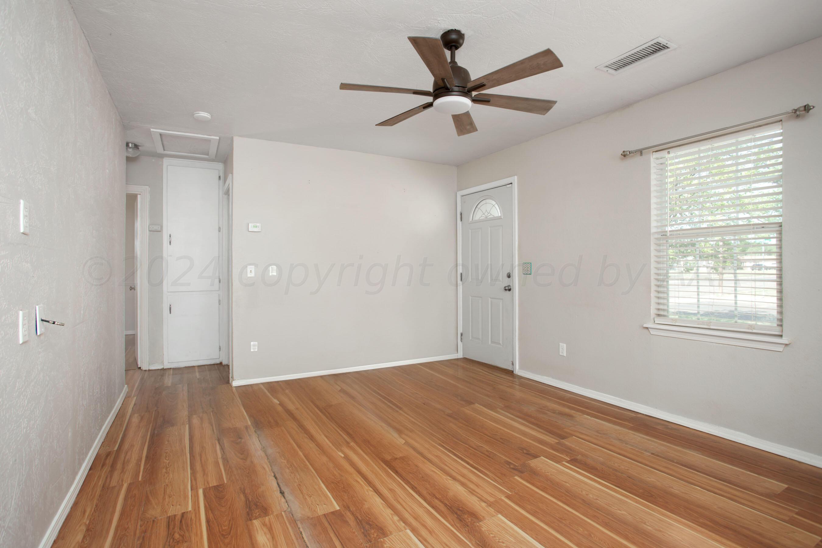 4625 South Travis Street Amarillo, TX 79110 - Photo 4 of 24 a view of a big room with wooden floor closet and windows
