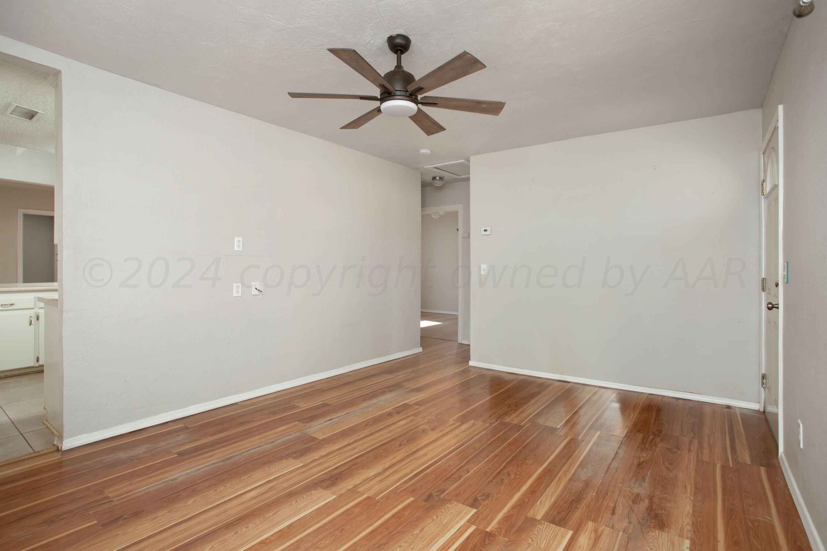 4625 South Travis Street Amarillo, TX 79110 - Photo 5 of 24 an empty room with wooden floor and ceiling fan