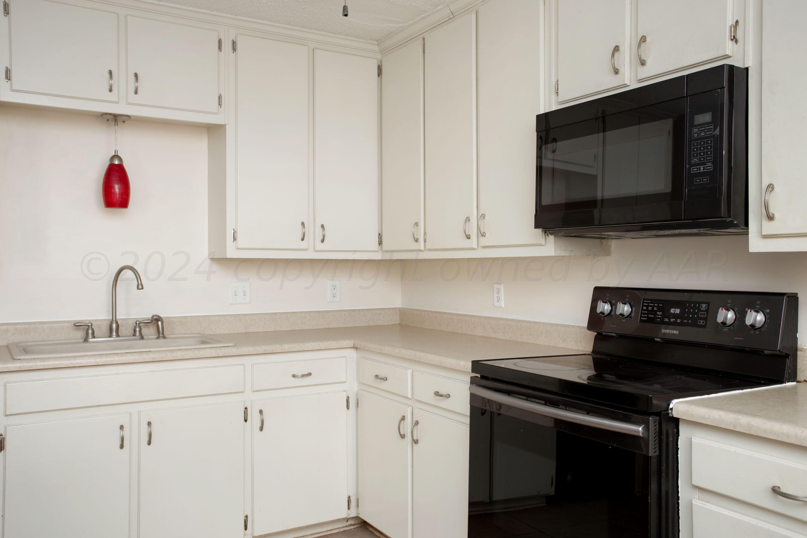 4625 South Travis Street Amarillo, TX 79110 - Photo 7 of 24 a kitchen with white cabinets and black appliances