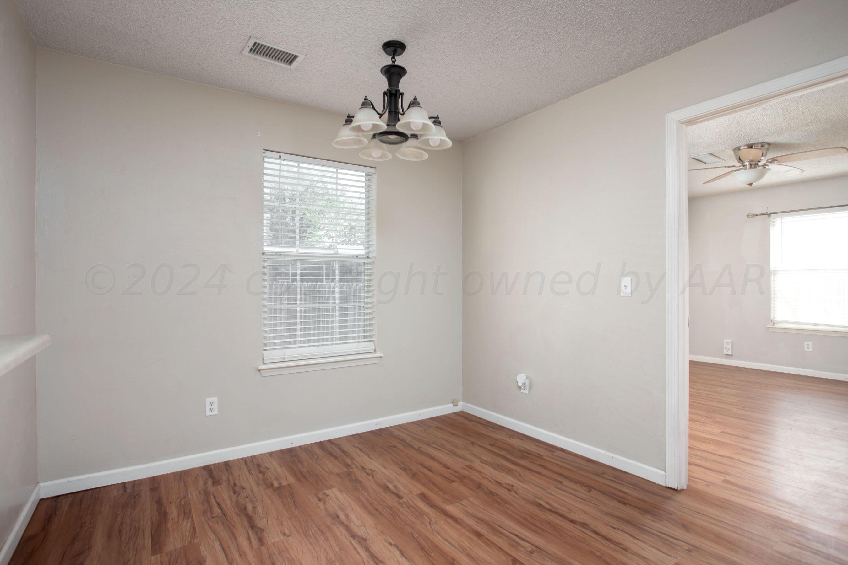 4625 South Travis Street Amarillo, TX 79110 - Photo 9 of 24 a view of an empty room with wooden floor and a window