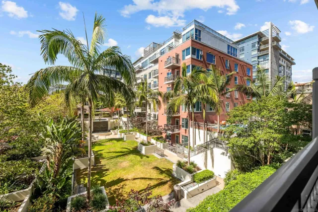 a front view of multi story residential apartment building with yard and sign board
