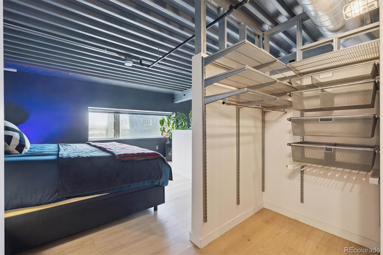 3457 Ringsby Court, Unit 304 Denver, CO 80216 - Photo 17 of 28 a room with a bed and a chandelier