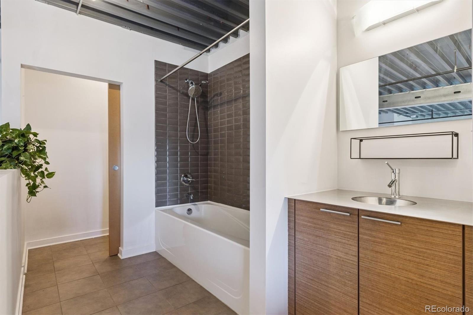 3457 Ringsby Court, Unit 304 Denver, CO 80216 - Photo 19 of 28 a bathroom with a bathtub and shower