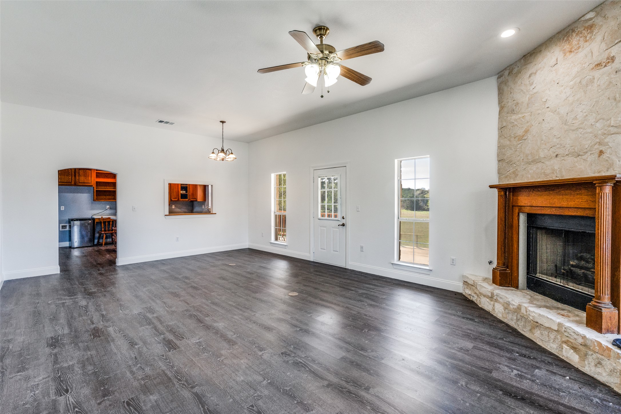 34970 Smithson Valley Road Bulverde, TX 78163 - Photo 9 of 36 an empty room with windows fireplace and a kitchen view