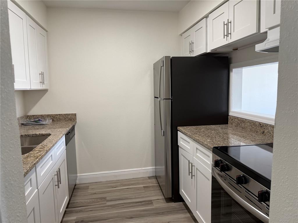 9209 Tudor Drive, Unit C102 Tampa, FL 33615 - Photo 2 of 8 a kitchen with stainless steel appliances granite countertop a refrigerator and a stove