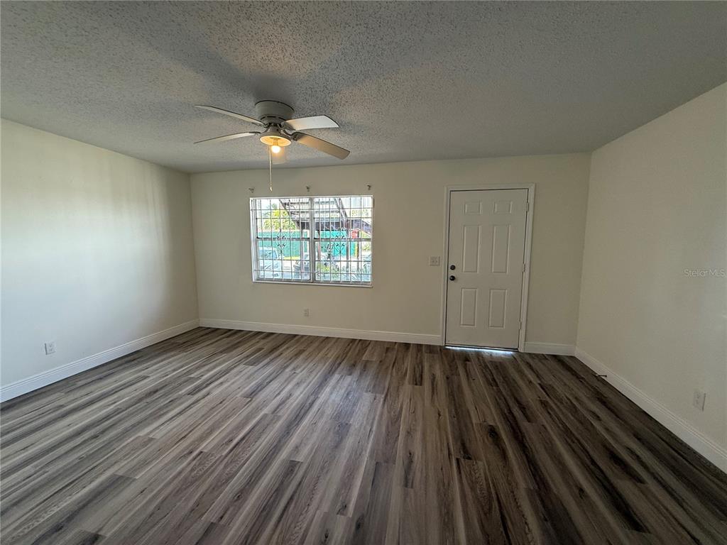 9209 Tudor Drive, Unit C102 Tampa, FL 33615 - Photo 4 of 8 an empty room with wooden floor chandelier fan and windows