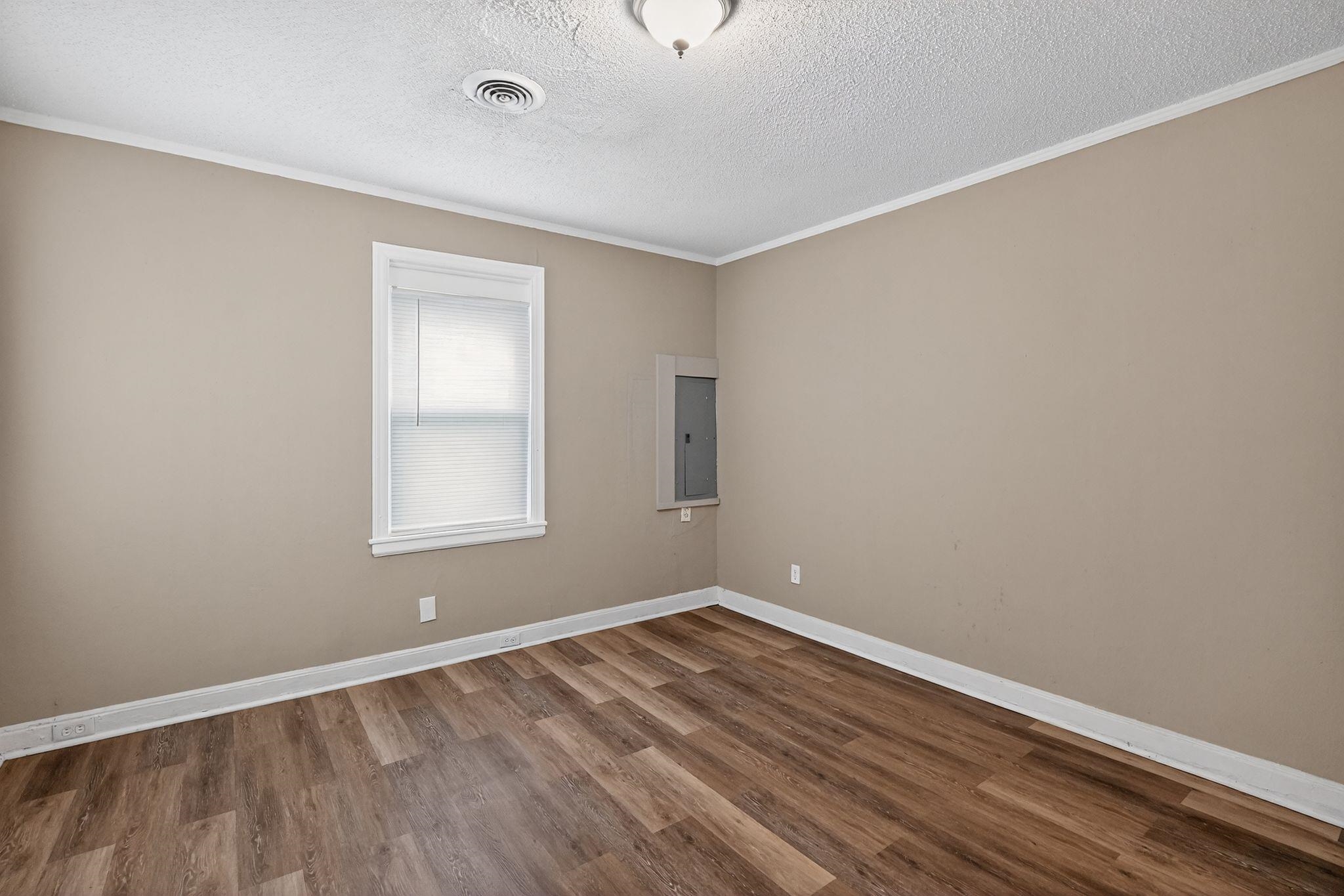 356 Hewlett Road Memphis, TN 38109 - Photo 15 of 30 Empty room featuring ornamental molding, wood finished floors, and a textured ceiling
