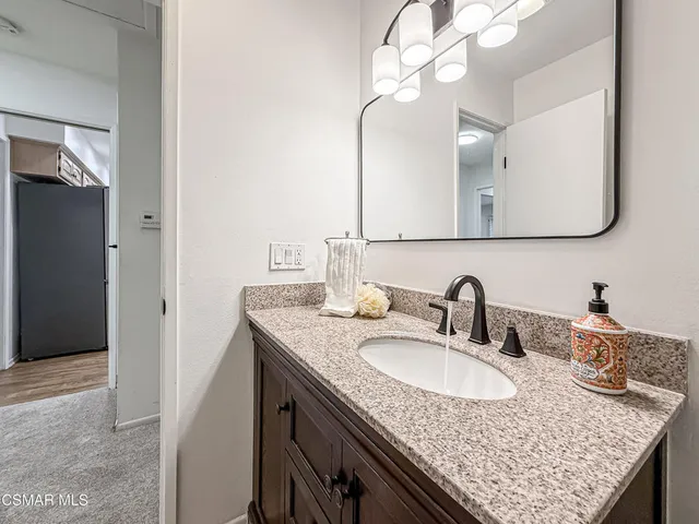 a bathroom with a granite countertop sink a mirror and vanity