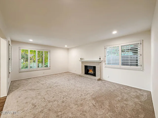 an empty room with windows fire place and natural light