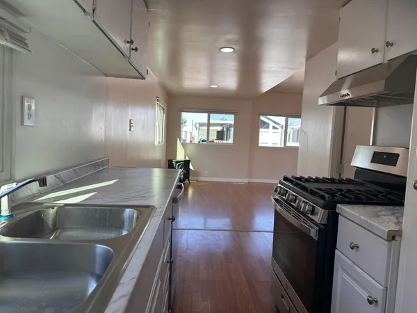 a kitchen that has a sink a stove and wooden floor