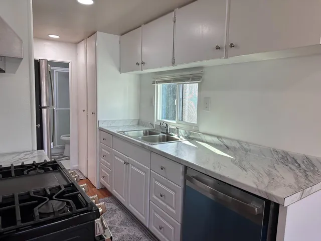 a kitchen with granite countertop a sink stove and refrigerator