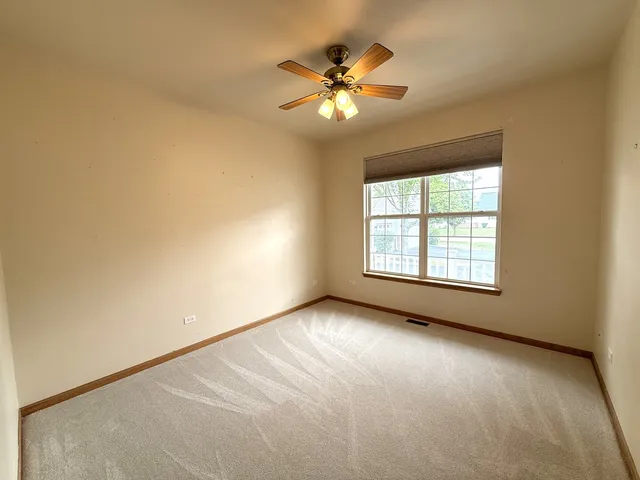 an empty room with chandelier fan and windows