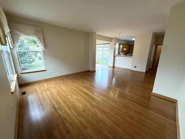 a view of an empty room with a window and wooden floor