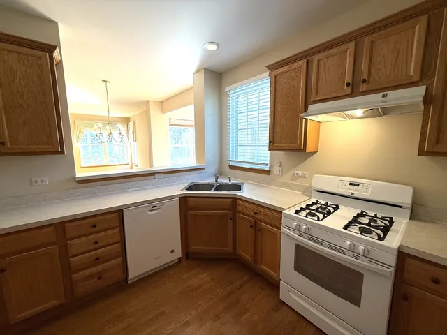 a kitchen with granite countertop wooden cabinets stove top oven and sink