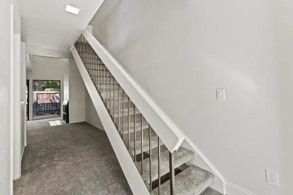 a view of staircase with railing and white walls