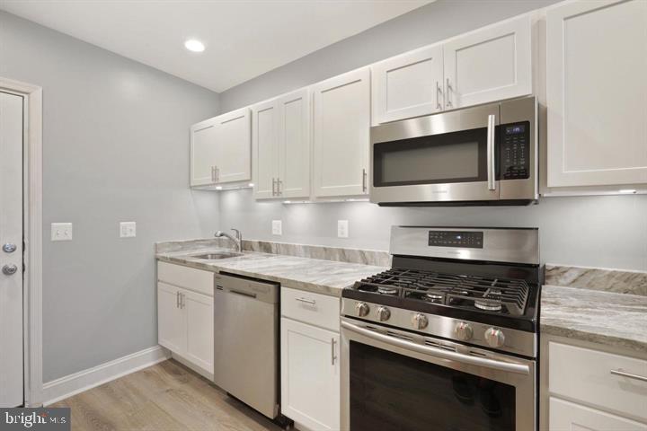 3541 3rd Street Baltimore, MD 21225 - Photo 5 of 37 a kitchen with stainless steel appliances granite countertop white cabinets a stove top oven