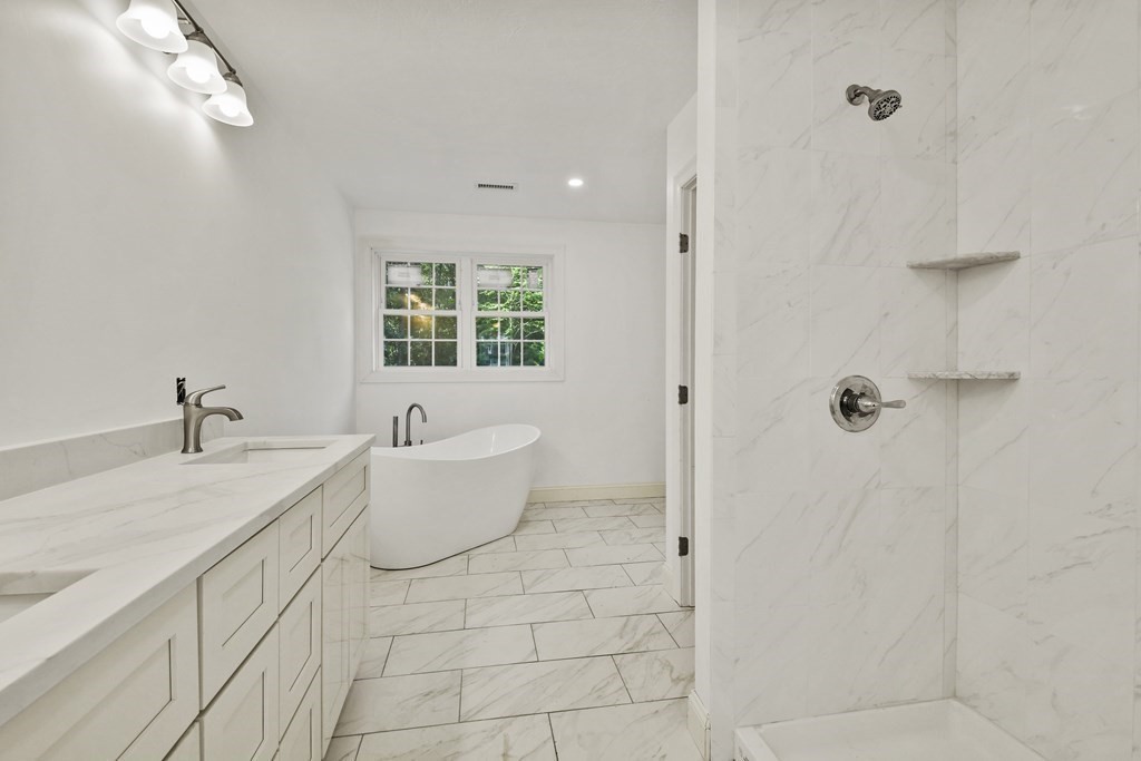 a bathroom with a granite countertop sink a toilet a mirror and bathtub