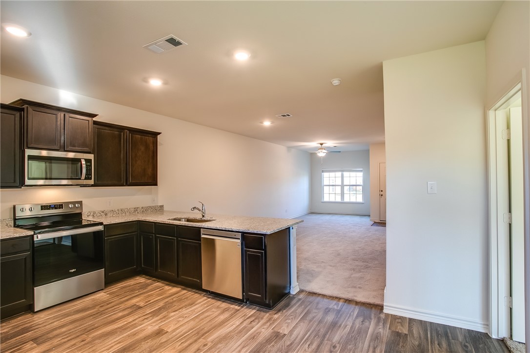 19024 Quiet Range Drive Elgin, TX 78621 - Photo 11 of 30 a kitchen with stainless steel appliances granite countertop a sink a stove top oven and wooden floors