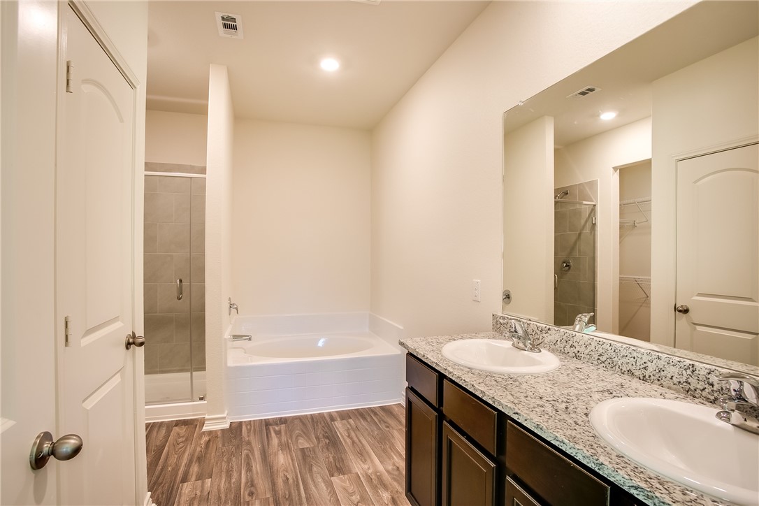 19024 Quiet Range Drive Elgin, TX 78621 - Photo 17 of 30 a bathroom with a granite countertop sink a mirror a bathtub and shower
