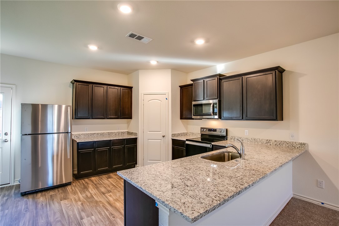 19024 Quiet Range Drive Elgin, TX 78621 - Photo 9 of 30 a kitchen with stainless steel appliances granite countertop a refrigerator microwave and sink