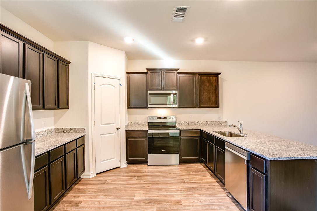 19024 Quiet Range Drive Elgin, TX 78621 - Photo 10 of 30 a kitchen with stainless steel appliances granite countertop a sink stove and refrigerator