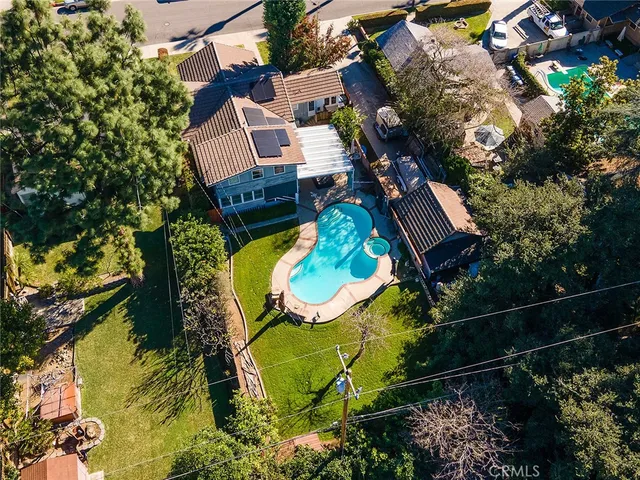 an aerial view of a house with swimming pool and large trees