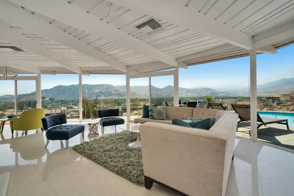 a living room with patio furniture and a floor to ceiling window