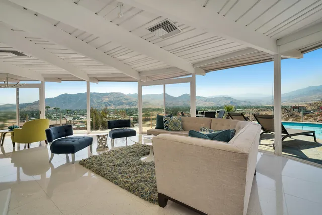 a living room with patio furniture and a floor to ceiling window