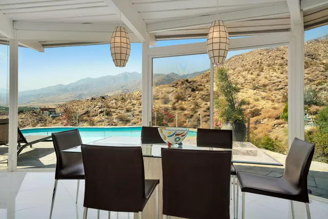 a dining room with furniture a chandelier and large windows