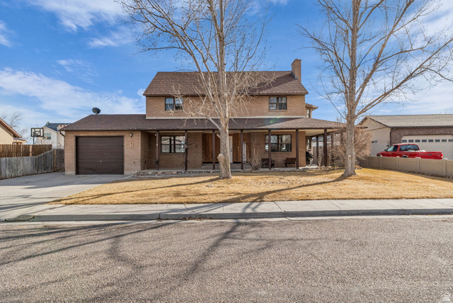 648 Tamarix Street Delta, UT 84624 - Photo 1 of 1 Traditional-style home with a garage, concrete driveway, brick siding, a chimney, and a porch