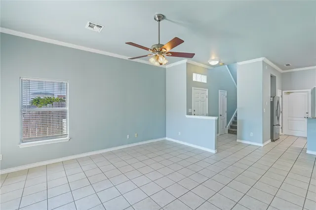 a view of an empty room with window and chandelier fan