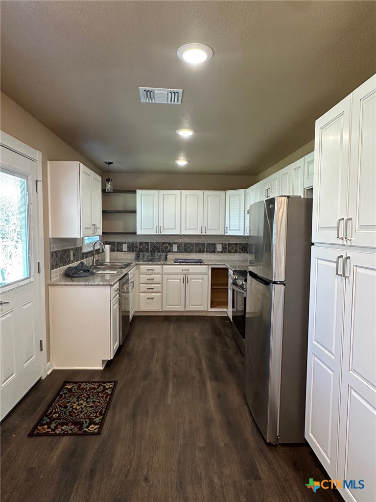 952 Fannin Loop Temple, TX 76501 - Photo 6 of 15 a kitchen with a refrigerator a stove and white cabinets