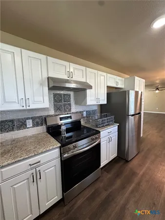 a view of a livingroom with wooden floor a ceiling fan and windows