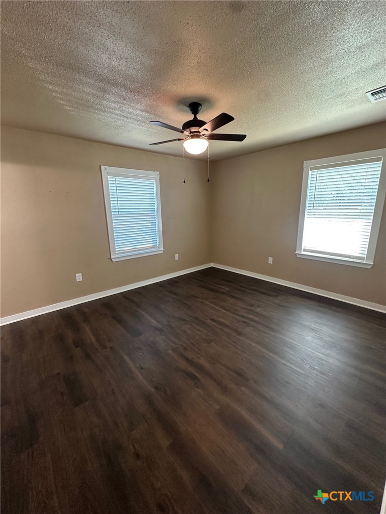 952 Fannin Loop Temple, TX 76501 - Photo 9 of 15 an empty room with wooden floor ceiling fan and windows
