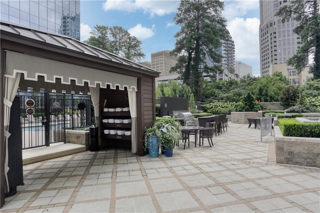 3445 Stratford Road Northeast, Unit 3703 Atlanta, GA 30326 - Photo 42 of 59 a view of a patio with dining table and chairs with a barbeque grill and a fireplace