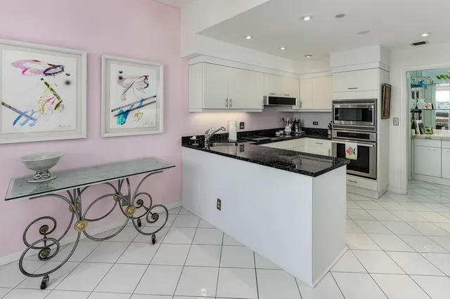 a kitchen with granite countertop a sink a stove a refrigerator and cabinets